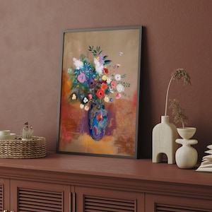 May include: A framed floral art print featuring a vibrant bouquet in a blue vase. The artwork showcases colorful flowers in shades of red, pink, blue, and white, set against a textured background. The frame is black.