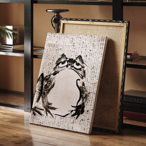 May include: A black and white illustration of a frog on a canvas print. The print is framed and has a white background with black text.