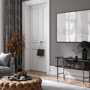 May include: A black and white line art print of the Dubai skyline hanging on a gray wall above a black console table with two shelves. The table has a black marble top and a black metal frame. A black lamp with a marble shade sits on the table.