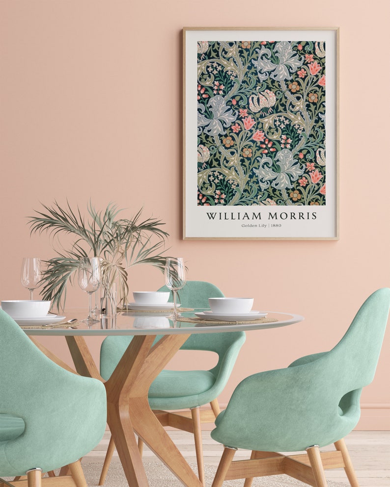 May include: A framed print of a floral pattern by William Morris, titled "Golden Lily" from 1880. The print is hanging on a pale pink wall above a dining table with four light green chairs.