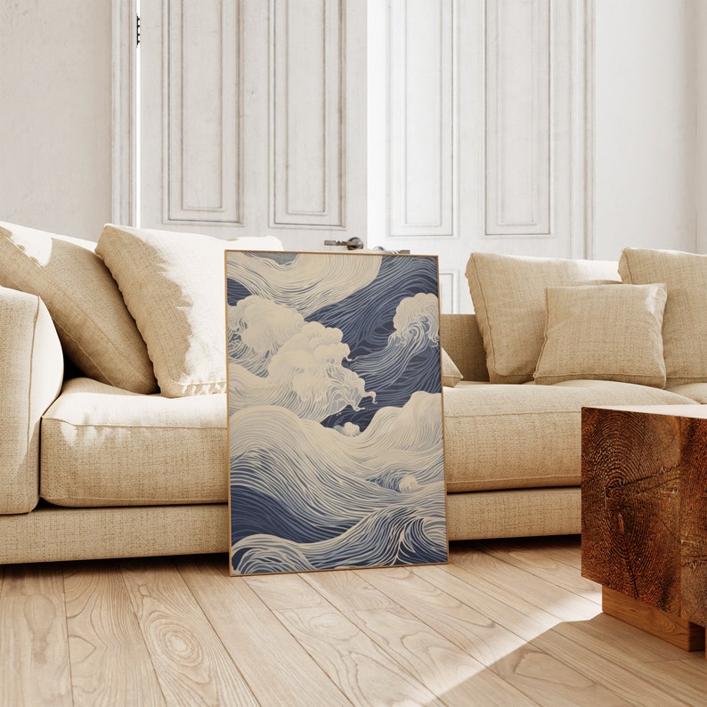 May include: A framed print of a blue and white abstract wave design. The waves are drawn with thin lines and create a sense of movement. The print is hanging on a wall in a living room.
