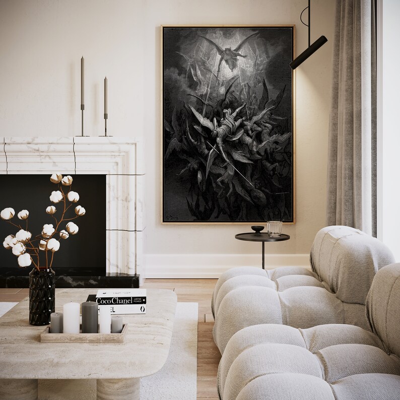 May include: A black and white print depicting a dramatic scene with angels and demons. The print is framed and hanging on a white wall above a white sofa.