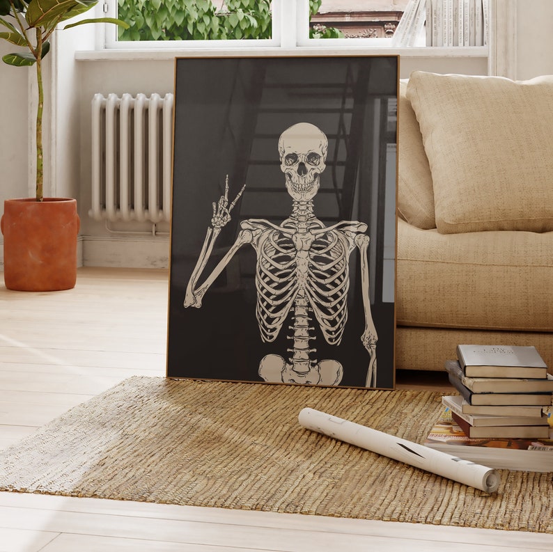 May include: A framed black and white illustration of a skeleton making a peace sign. The skeleton is in a standing pose with its arms outstretched. The background is black.
