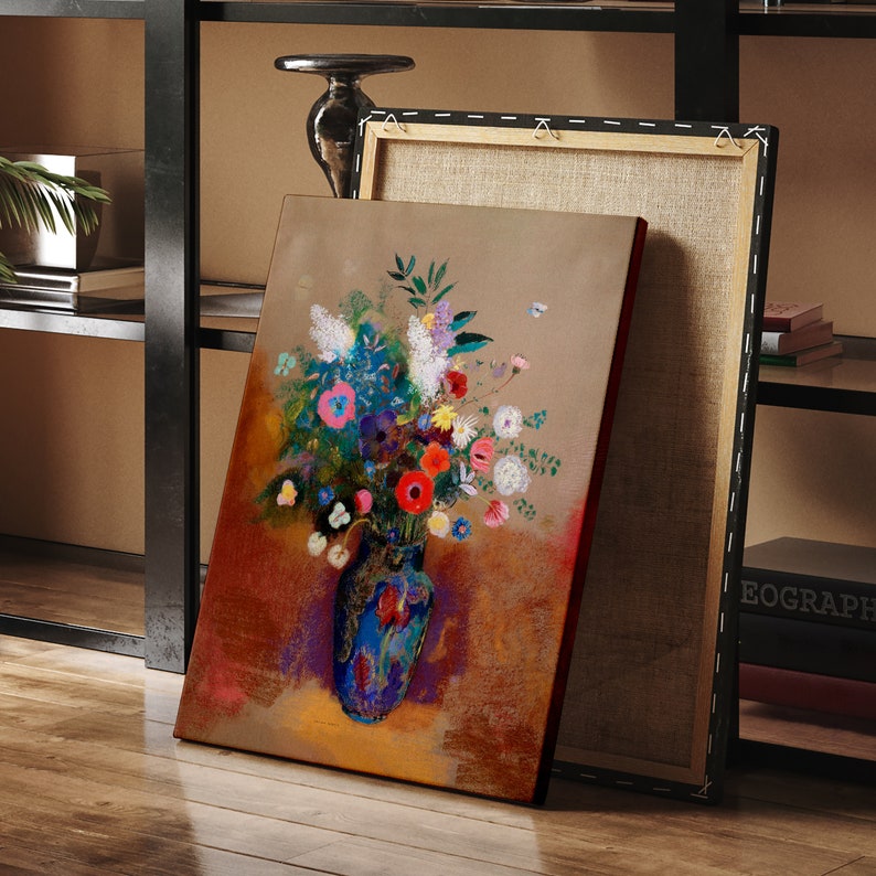 May include: An abstract painting of a vibrant floral arrangement in a blue vase. The artwork features a bouquet of colorful flowers, including red, pink, and white blooms, set against a warm, earthy background. The canvas is leaning against another canvas.