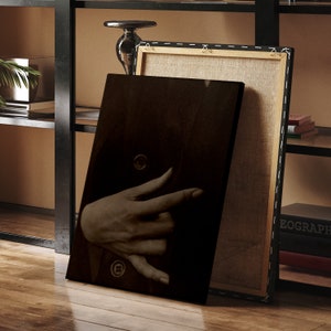 Op de afbeelding: Een close-up van een hand die uit een donkere achtergrond reikt. De hand is gedeeltelijk bedekt door een donker jack met een knoop. De afbeelding is in zwart-wit.