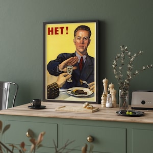 May include: A vintage-style poster with a yellow background and a man in a suit saying "HET!" while gesturing with his hand. The man is seated at a table with a plate of food and a glass of liquid.