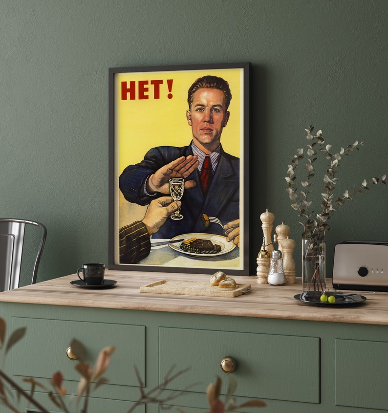 May include: A vintage-style poster with a yellow background and a man in a suit saying "HET!" while gesturing with his hand. The man is seated at a table with a plate of food and a glass of liquid.