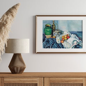 May include: A framed still life painting of a green vase, a white pitcher, and a bowl of apples on a blue and white patterned tablecloth. The painting is in a light blue, white, and green color scheme.