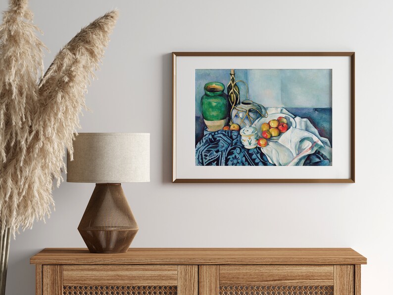May include: A framed still life painting of a green vase, a white pitcher, and a bowl of apples on a blue and white patterned tablecloth. The painting is in a light blue, white, and green color scheme.