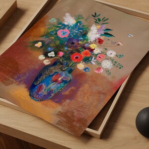 May include: A colorful floral still life painting featuring a blue vase filled with a vibrant bouquet of flowers. The artwork is set against a brown background and framed in a light wooden frame. The flowers include red, pink, white, and blue blooms.