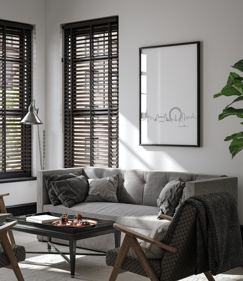 May include: A gray sofa with black throw pillows sits in a living room with wood blinds, a black coffee table, and a framed print of the London skyline with the text "London".