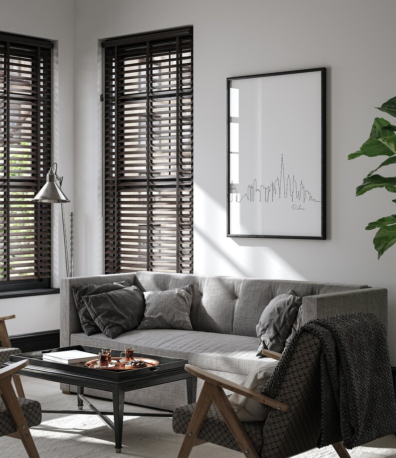 May include: A living room interior with a gray sofa, two chairs, a coffee table, and a framed print of the Dubai skyline. The room has wood blinds on the windows and a lamp on the floor.