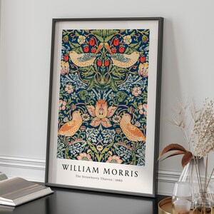 Op de afbeelding: Een ingelijste print van een vintage bloemenpatroon met vogels en bessen. De print is getiteld "William Morris, The Strawberry Thieves, 1883".