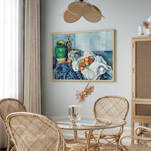 May include: A still life painting of a green ceramic vase, a white ceramic pitcher, and a bowl of red apples on a blue and white tablecloth. The painting is framed and hanging on a light blue wall.