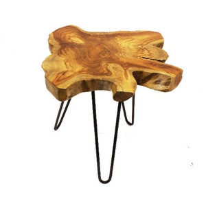 May include: A natural wood side table with a unique, irregular shape and a live edge top. The table has three black hairpin legs.