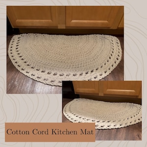 Op de afbeelding: Een beige keukenmat van katoenen koord met een gehaakt ontwerp. De mat heeft de vorm van een halve cirkel en ligt onder een keukenkastje.