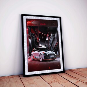 May include: Framed print featuring a white and black Audi car with red accents. The image includes interior details and the Audi logo. The artwork is displayed on a wooden floor, leaning against a white wall.