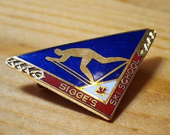 May include: A triangular gold pin with a blue background and a skier in silhouette. The pin says "Sigge's Ski School" in gold lettering.