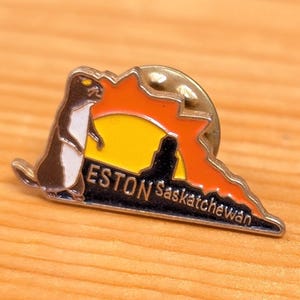 May include: A white ceramic mug with a black handle and the text "But First, Coffee" in a bold, black font. The mug is set against a blurred background, suggesting a cozy setting. The mug appears to be approximately 4 inches tall.