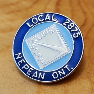 May include: A blue and silver pin with the text "LOCAL 2875 NEPEAN ONT." and a white square with the text "CUPE SCEP" inside.