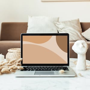 Puede incluir: Un ordenador portátil con un diseño abstracto marrón, beige y blanco en la pantalla. El portátil está sobre una mesa blanca con una pequeña escultura blanca y hierbas secas.