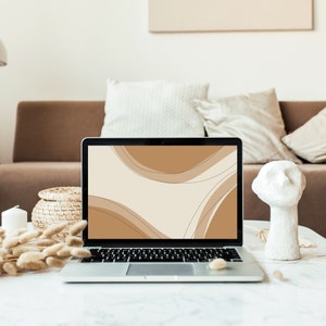 Puede incluir: Un ordenador portátil con un fondo blanco y formas abstractas marrones en la pantalla. El portátil está sobre una mesa de mármol blanco con una escultura de cerámica blanca y hierbas secas.