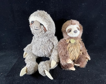 May include: Two plush sloth toys. One is brown with a light brown face and the other is gray with a light brown face.