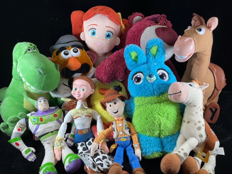 May include: A collection of plush toys featuring characters from the Toy Story franchise. The toys include Woody, Buzz Lightyear, Jessie, Rex, Lotso, Mr. Potato Head, and others. The toys are brightly colored and made of soft materials.