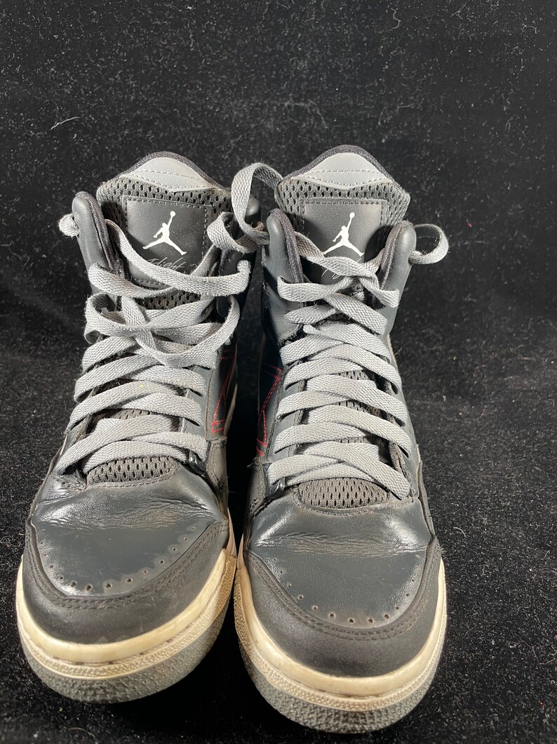 May include: A pair of black and gray high-top sneakers with gray laces and a white Jumpman logo on the side.