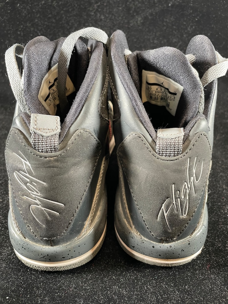 May include: A pair of black leather high-top sneakers with a white sole and gray accents. The sneakers have a signature "Flight" inscription on the back.