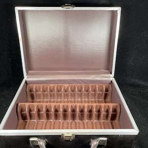 May include: Open brown suitcase with a silver frame and handle. The interior features a brown lining and dividers. The case is designed to hold items securely. The case is on a black background.