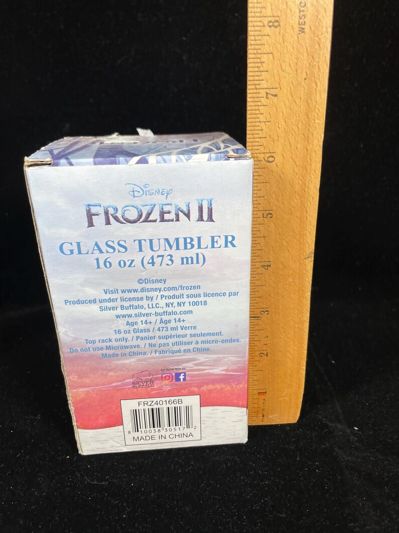 May include: A Disney Frozen II glass tumbler in a box. The box is white and blue with the Frozen II logo and text. The tumbler holds 16 oz (473 ml). The box also includes product information and a barcode.