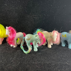 May include: A collection of six vintage My Little Pony toys. The ponies are all different colors and have different hairstyles. They are all in good condition and have no missing parts.