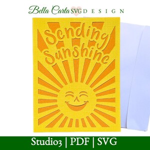 以下が含まれることがあります： 笑顔の太陽のデザインと「Sending Sunshine」の文字が切り抜かれた黄色のカード。太陽は放射線状の線を持っています。白い封筒がカードの隣にあります。このカードはStudio3 PDFおよびSVGデザインです。