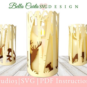 Könnte beinhalten: Drei beigefarbene Papier-Kerzenhalter mit einem ausgeschnittenen Design einer Waldszene mit Hirschen. Die Kerzenhalter stehen auf einer hellbraunen Holzoberfläche. Studio3 | SVG | PDF Instructions.