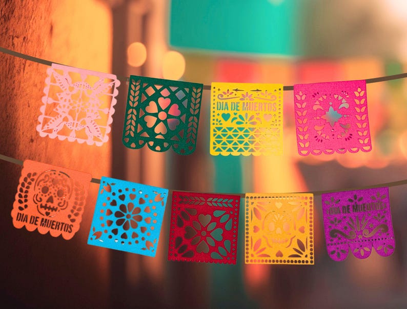 May include: A string of colorful paper banners with cut-out designs, including skulls, flowers, and the text "Dia de Muertos".