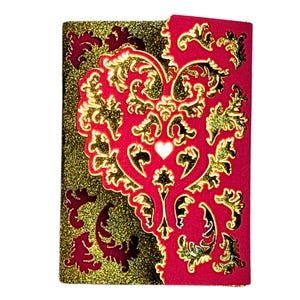 May include: A red and gold card with a decorative heart design. The heart is made of gold glitter and has a smaller white heart in the center.