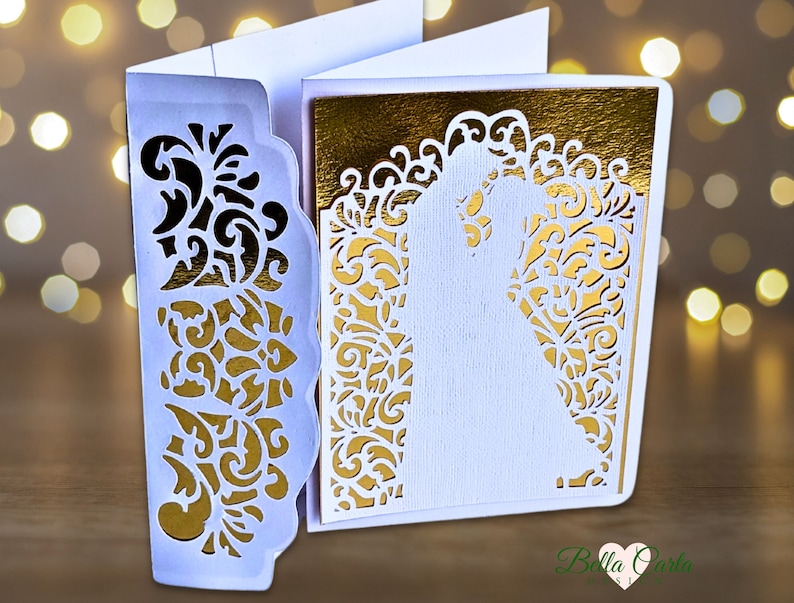 May include: A white and gold laser-cut wedding invitation card featuring an intricate filigree pattern on the front flap and a silhouette of a couple embracing on the main panel, set against a metallic gold background with a scalloped edge design.