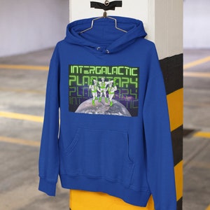 May include: A royal blue hooded sweatshirt with a graphic print of three figures in green and white standing on a planet. The text "INTERGALACTIC PLANETARY" is repeated in green letters.