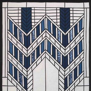 Könnte beinhalten: Eine Steppdecke mit geometrischem Muster auf weißem Hintergrund und blauen und schwarzen Linien. Das Muster erinnert an ein Buntglasfenster.