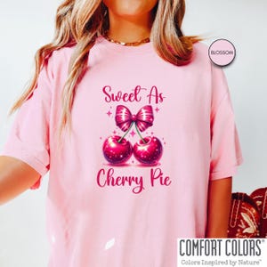 May include: Pink t-shirt with the text "Sweet As Cherry Pie" and a graphic of two red cherries with a pink bow on top.