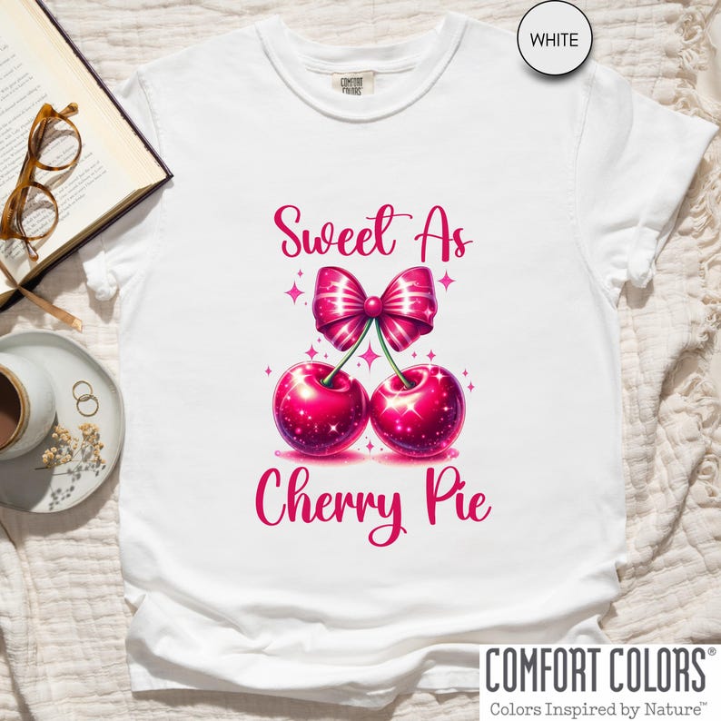 May include: White t-shirt with a pink cherry pie design and the text "Sweet As Cherry Pie".