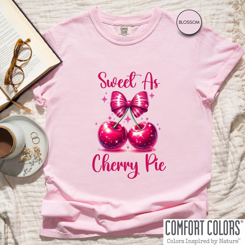 May include: Pink t-shirt with the text "Sweet As Cherry Pie" and a graphic of two red cherries with a pink bow.