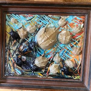 May include: A framed mixed media artwork featuring a collage of horseshoe crabs and black insects on a colorful background with blue, orange, and yellow hues.