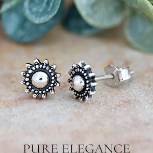 May include: A pair of silver stud earrings with a sunburst design. The earrings are small and delicate, and they would make a great gift for a friend or loved one.