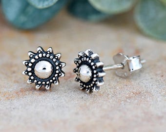 May include: A pair of silver stud earrings with a sunburst design. The earrings are small and delicate, and they would make a great gift for a friend or loved one.