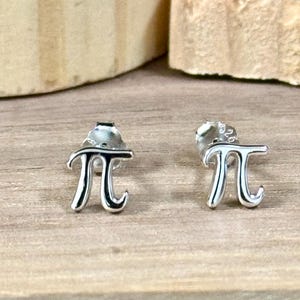 May include: A pair of silver earrings shaped like the mathematical symbol pi.