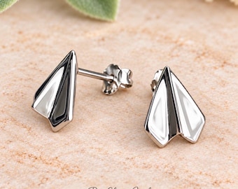 May include: A pair of silver-toned stud earrings shaped like paper airplanes. Each earring features a polished, reflective surface with defined geometric folds. The earrings include standard post backs and are marked with the text PureEleganceJewelz.