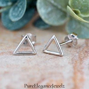 May include: A pair of silver triangle stud earrings. The earrings are simple and minimalist, with a hollow triangle design.