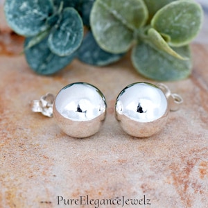 May include: A pair of silver ball stud earrings. The earrings are round and have a smooth, shiny finish.